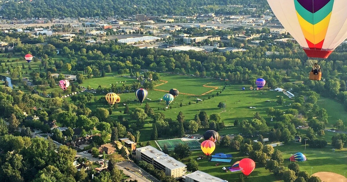 Dozens of hot air balloons float over a green area near Boise, part of the city's retail and tourists attractions