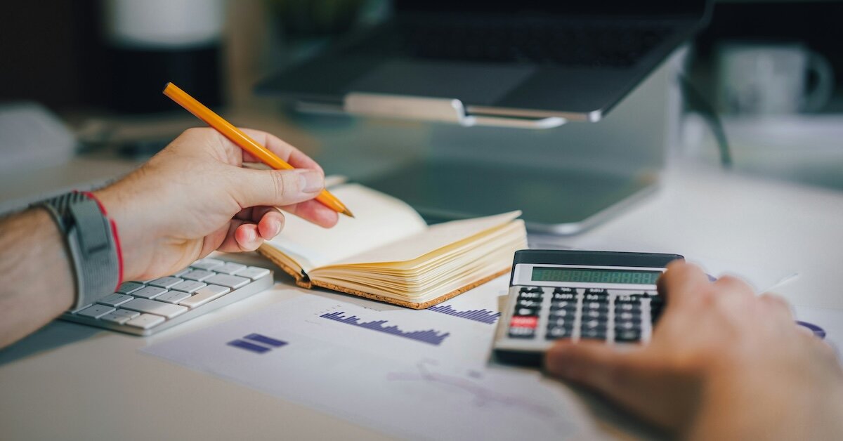 A lefthanded person doing calculations by hand and with a calculator