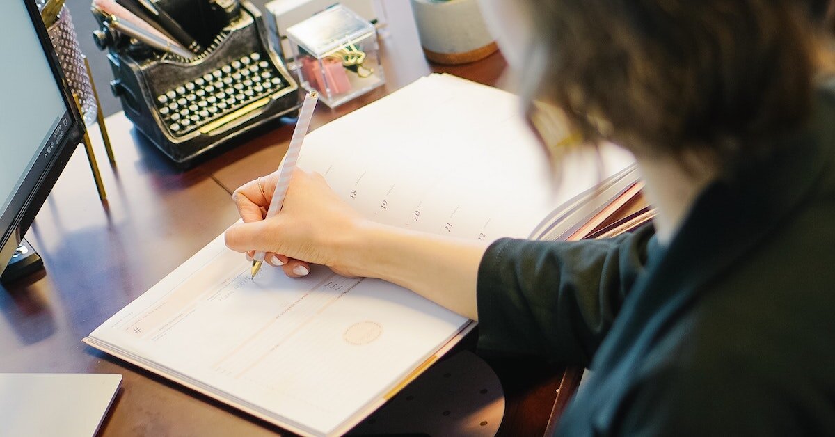 A broker writes her next appointment in her calender.