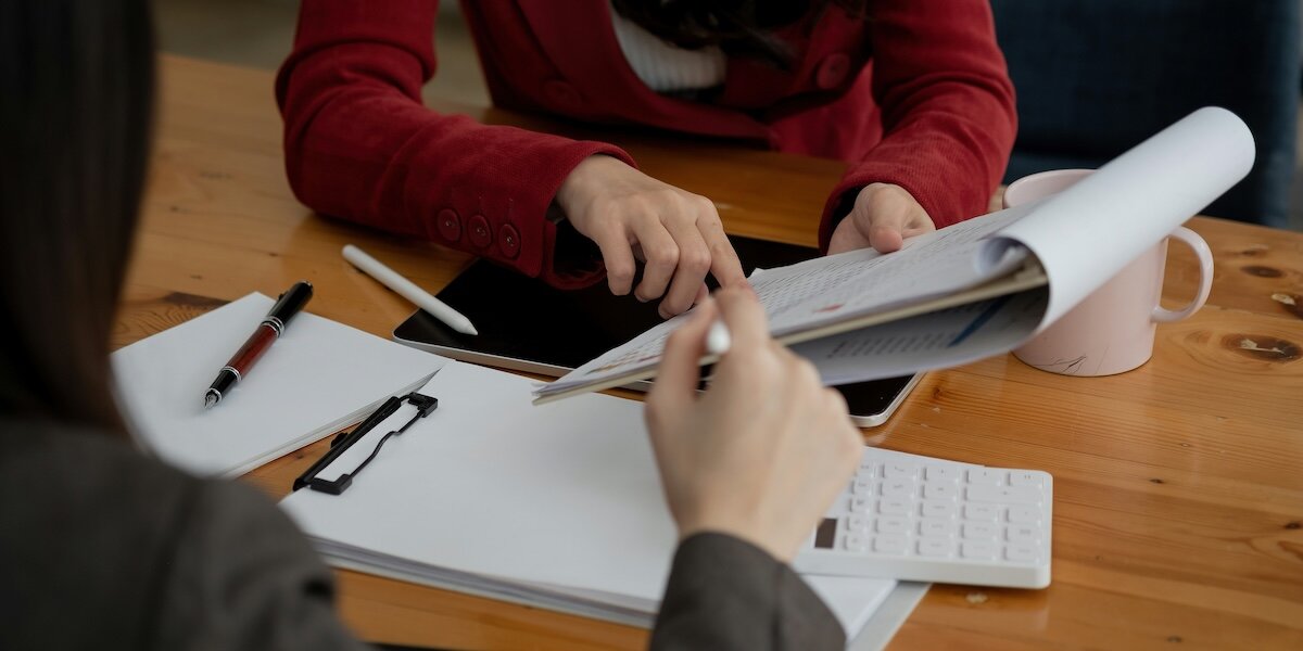 two business professionals with calculators, clipboards and documentation performing an appraisal