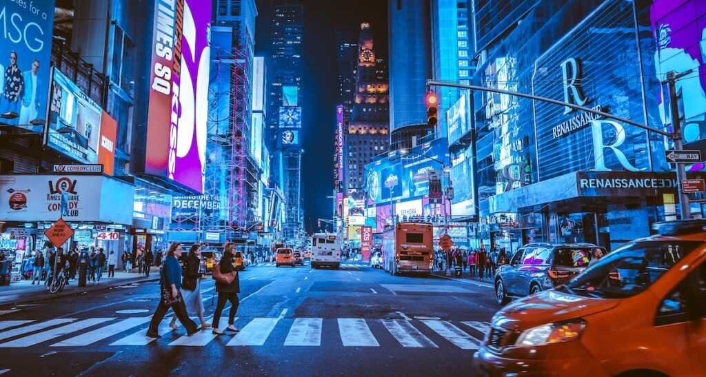 People walking through a highly lit Times Square at night