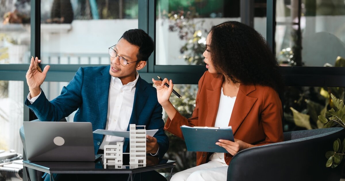 Two individuals discussing paperwork and working on getting a deal done