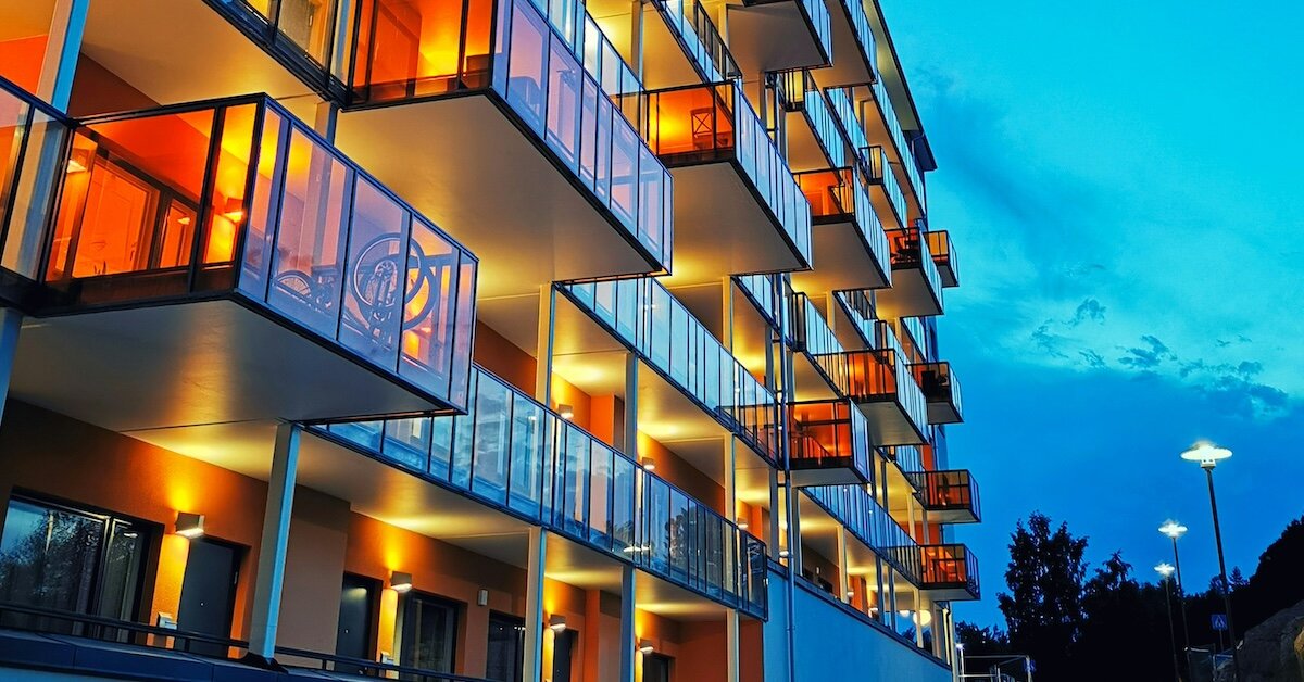 A student housing building with lit up balconies at sunset