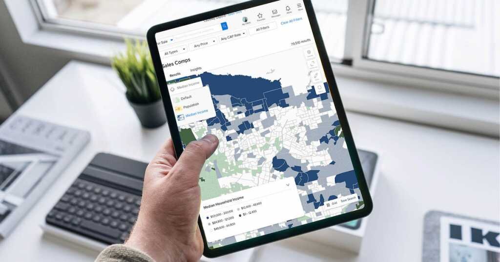 an ipad shows Crexi's map overlays in action, held in front of a desk