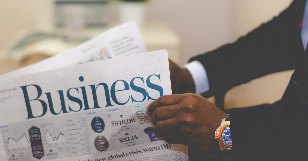 A person reviews the business section of a newspaper