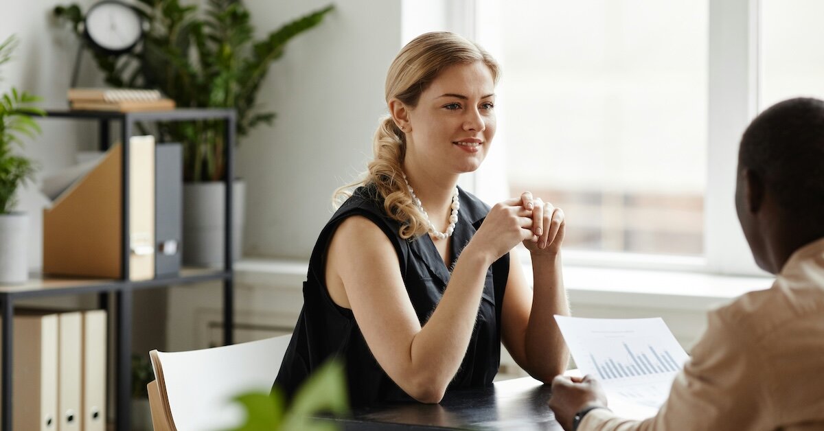 Two professional women sit at a desk for a meeting