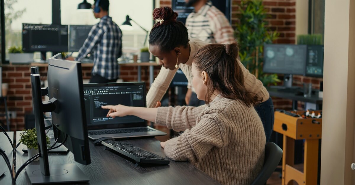 Two people are sitting on a conference call reviewing code for a software program