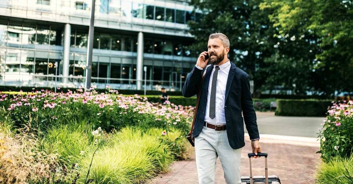 A business man talks on the phone walking through the common area of an office park