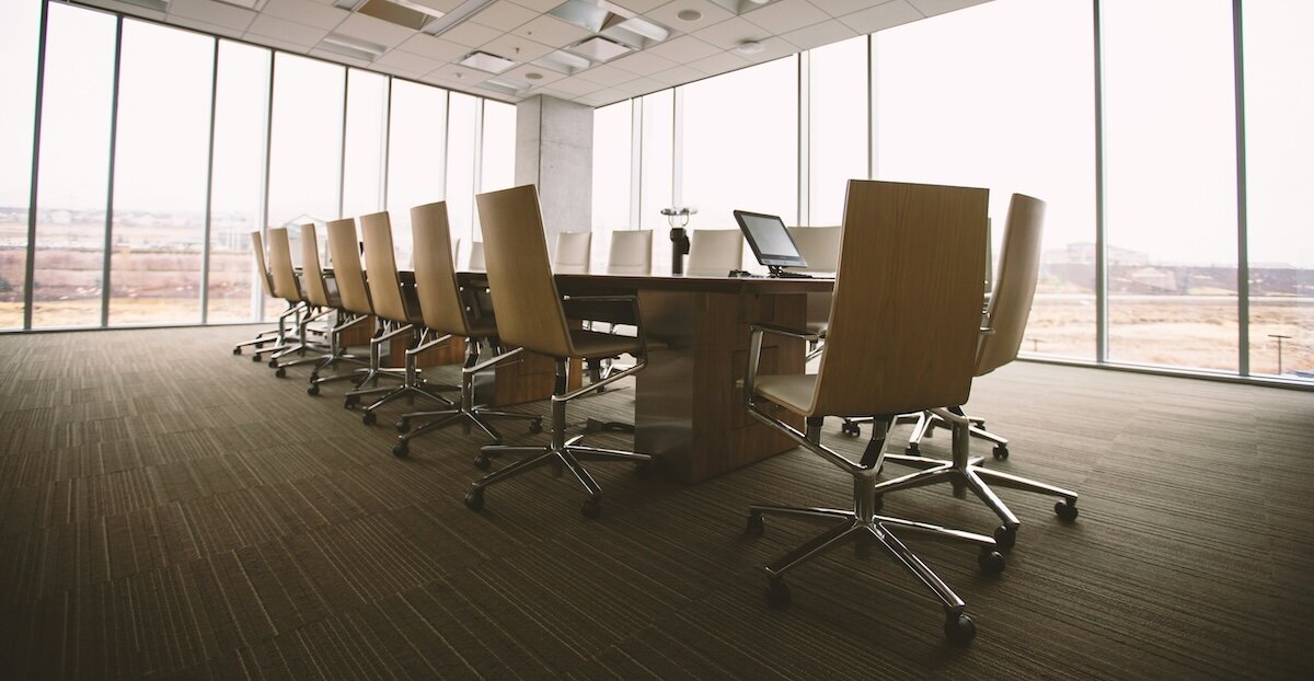 An empty conference room stands with chairs tucked into a large office table