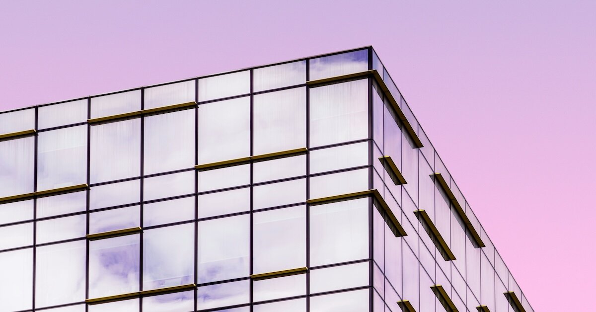 A commercial building reflecting pink against the sunset sky 