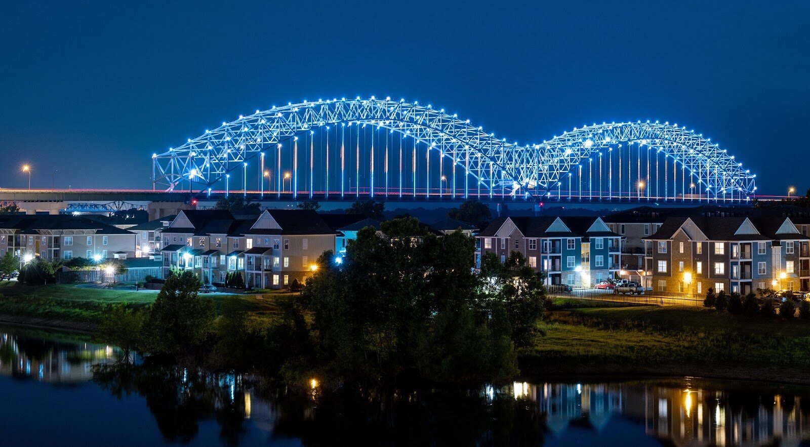 A Memphis bridge lit up at night with multifamily housing in the foreground