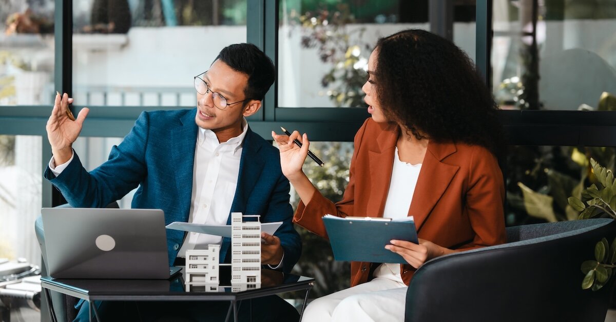 A man and woman review technical documents, on which a cap rate exists, as they evaluate a commercial real estate deal