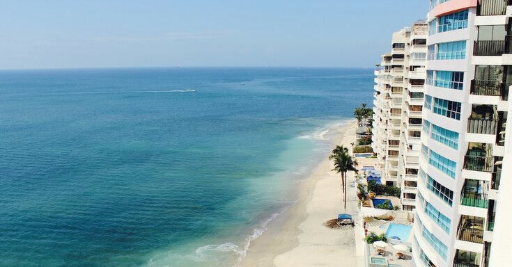 A hotel faces the Gulf of Mexico, with palm trees lining the building