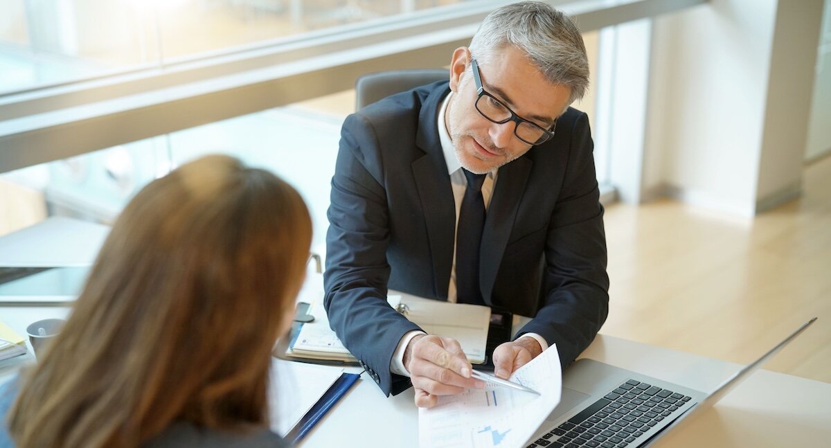 A businessman showing a woman options for financing, including balloon payments