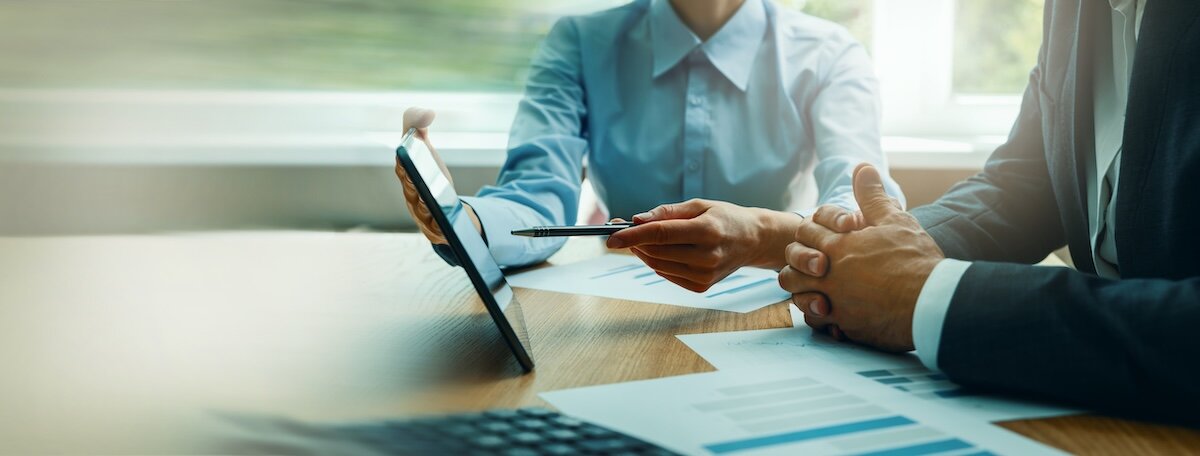 Two professionals reviewing documents on an ipad that display properties for syndication