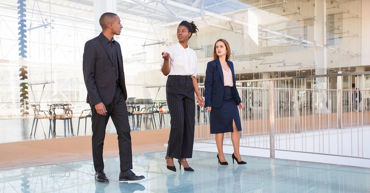 Three business professionals walk through a commercial building and evaluating investment decisions