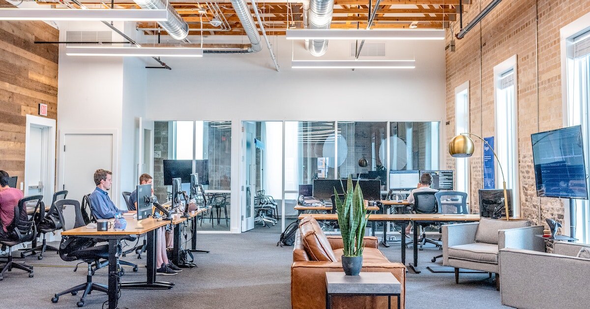 Modern office space with desks, monitors, and couch seating
