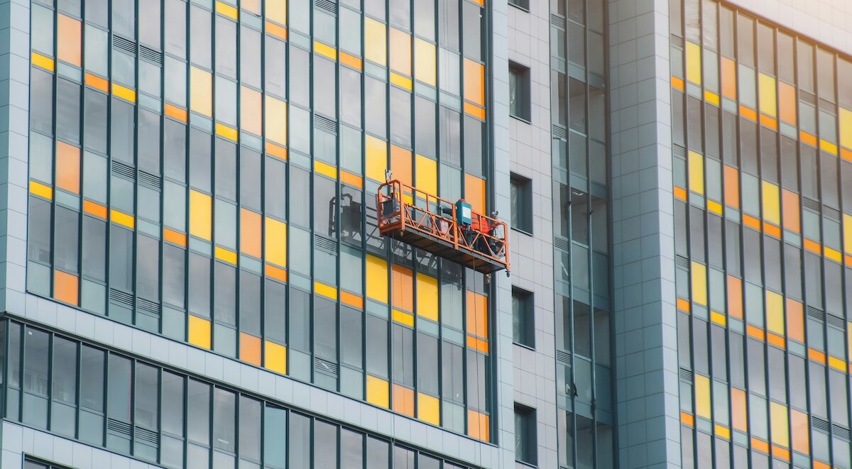 A window-cleaning unit hangs aside a commercial property skyscraper