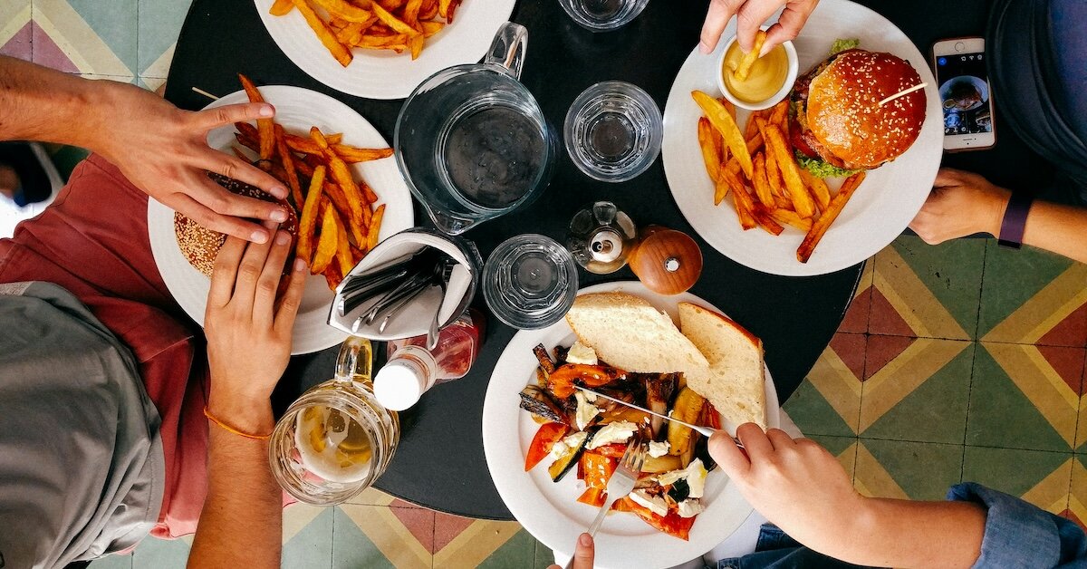 People sit around a small restaurant table with burgers and fries atop