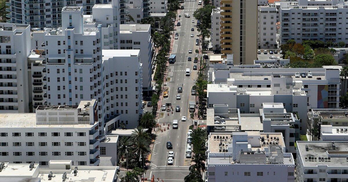 A main street in a city with cars driving between skyscrapers