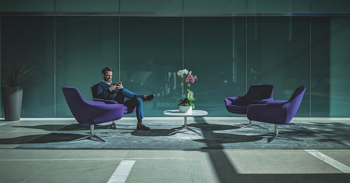 a broker in an office lobby reviewing comps and research on his phone