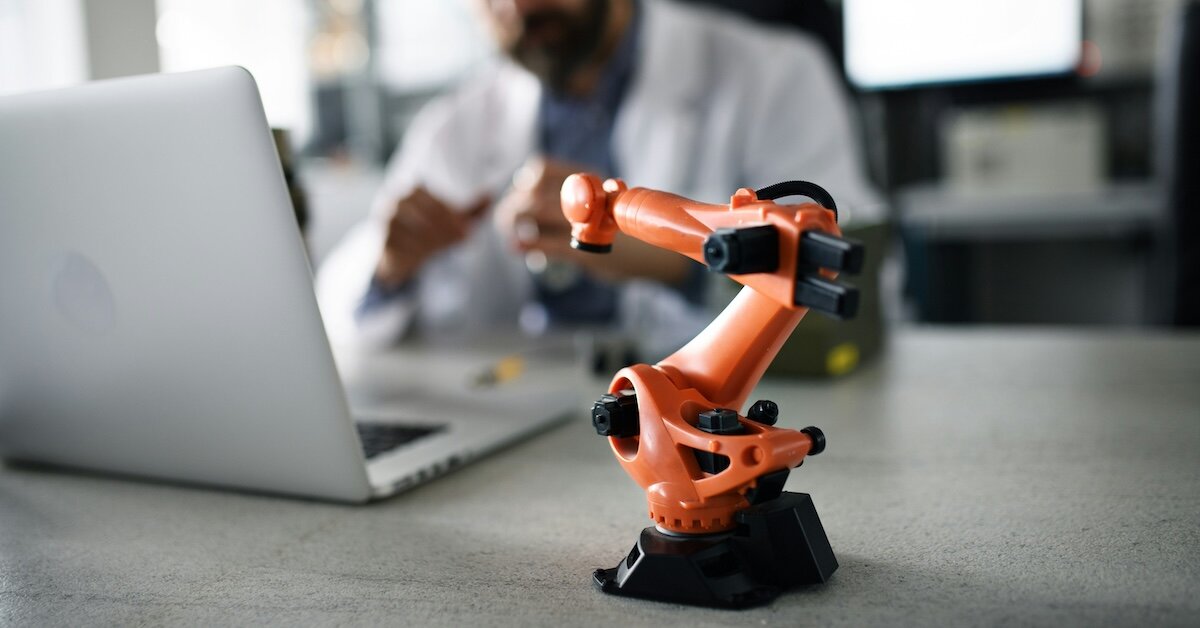 a little robot helps a person doing research on their laptop