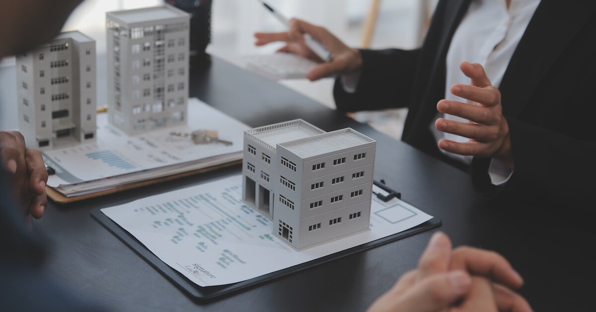 A model commercial building sits on top of a loan application on a clipboard