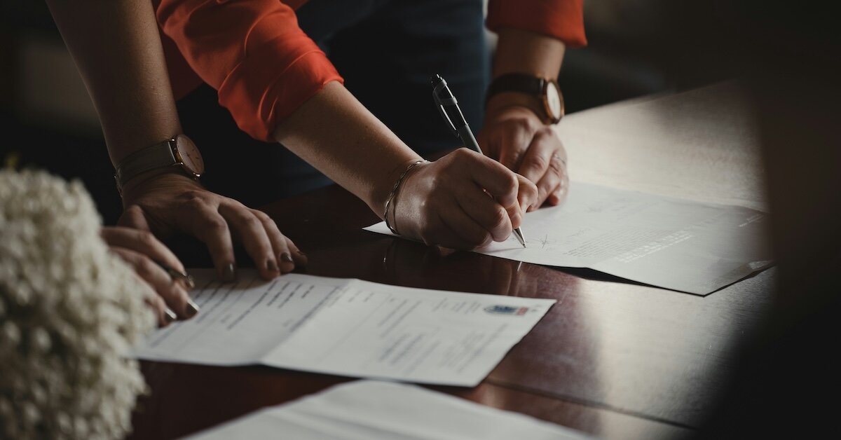 a woman signing a contract full of commercial real estate terms