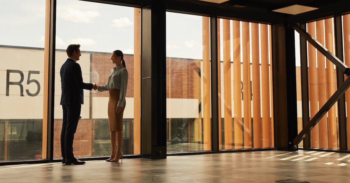 A woman shakes hands with a business man in an empty commercial real estate building