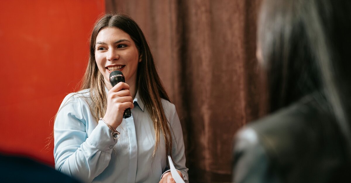 Woman public speaking with a mic at a podium