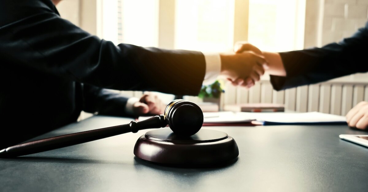 Two business professionals shaking hands next to an auction gavel
