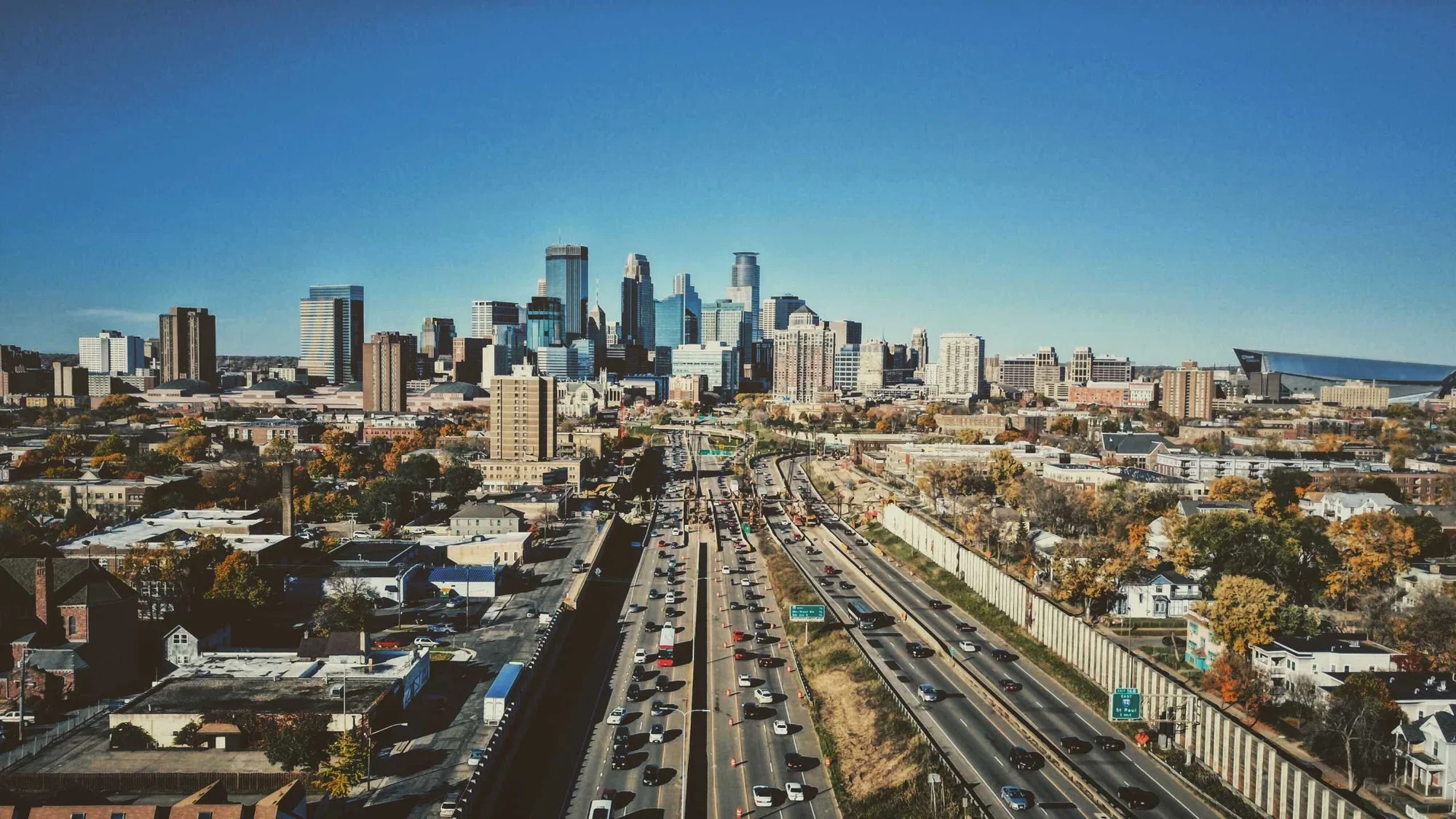A view of cars driving into downtown Minneapolis with plenty of commercial real estate buildings lining the road