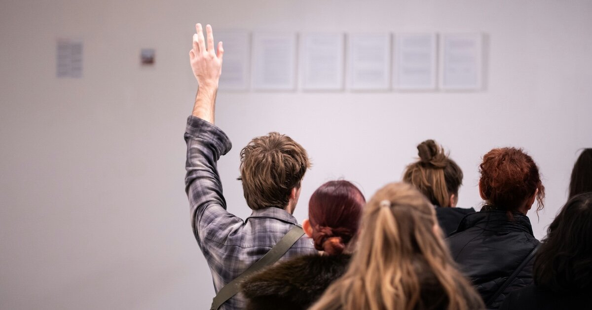 A person raises their hand to bid at an auction event