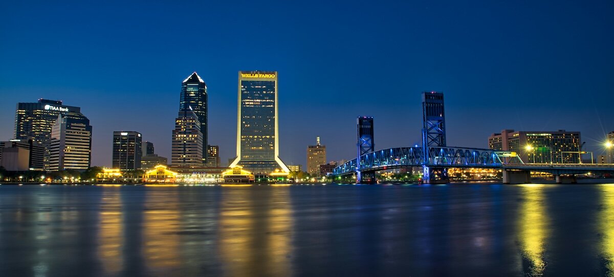The skyline of Jacksonville Florida at night with lights reflecting off the bay