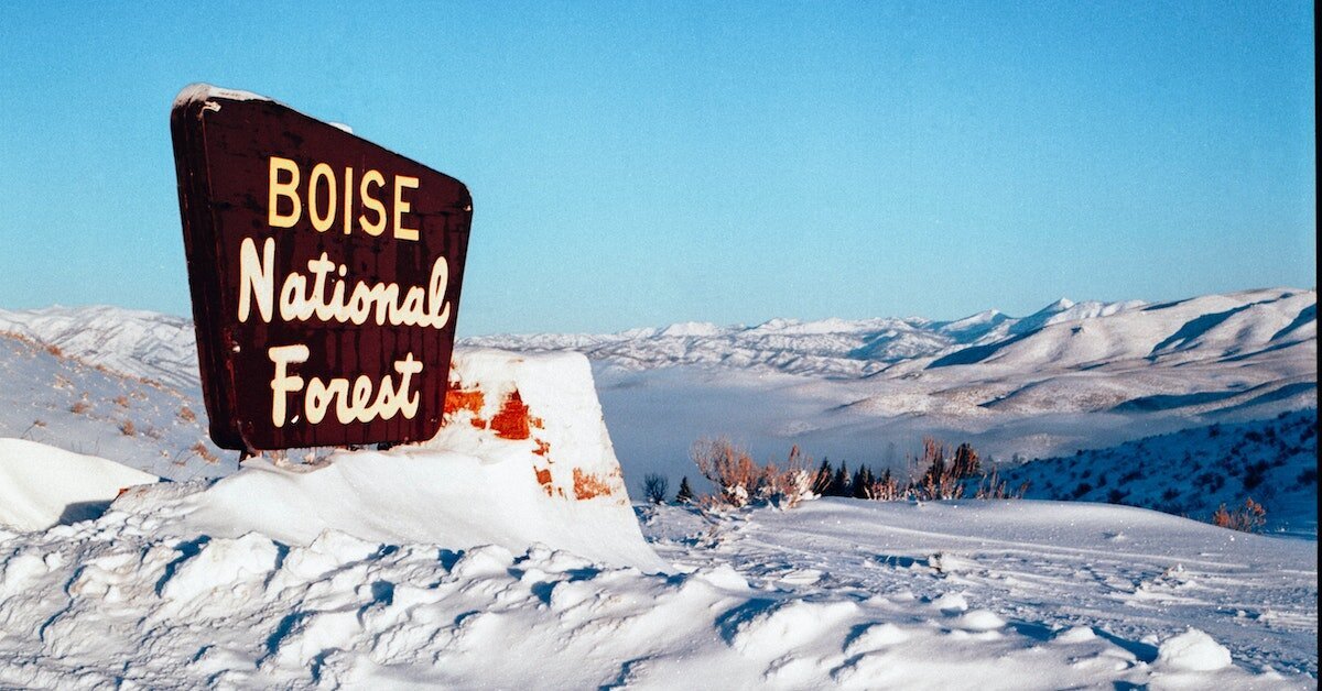 A snowcapped mountain with the sign "Boise National Forest" in the foreground