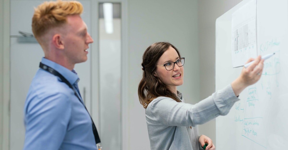 Scientist showing coworker whiteboard calculations