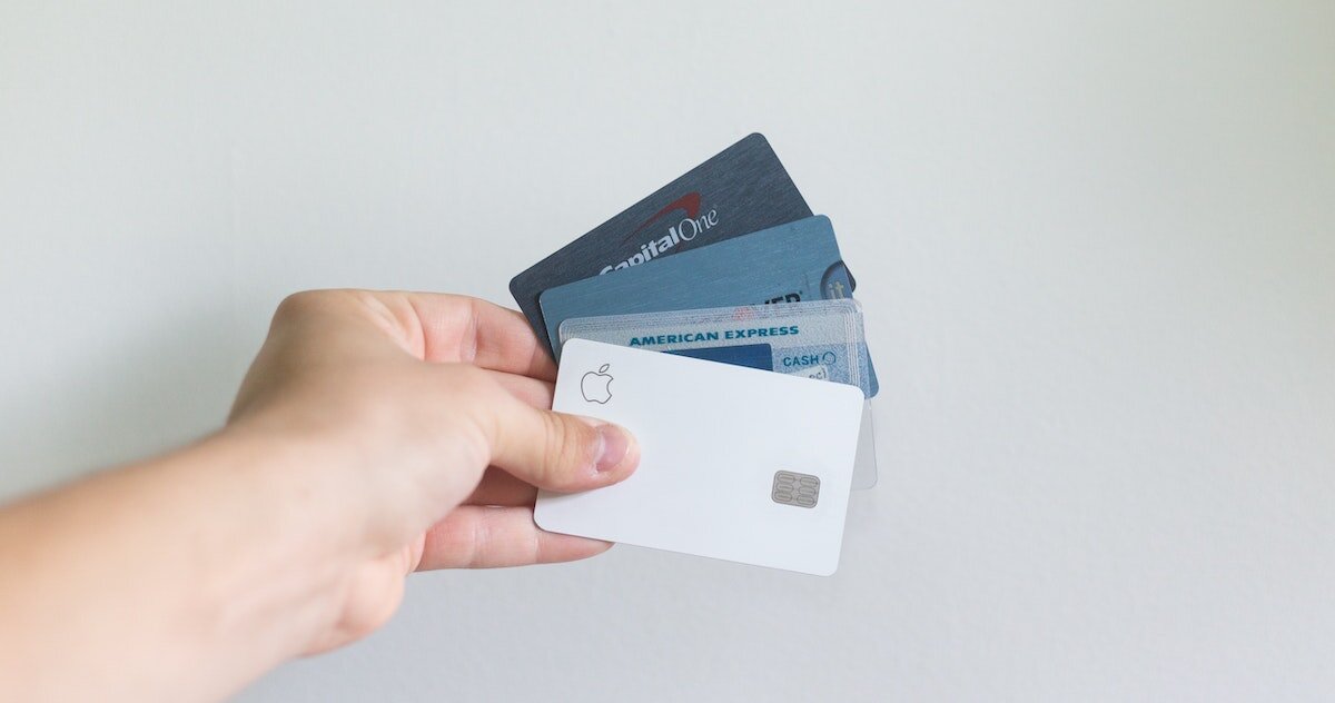 a hand holds out a few different types of business credit cards
