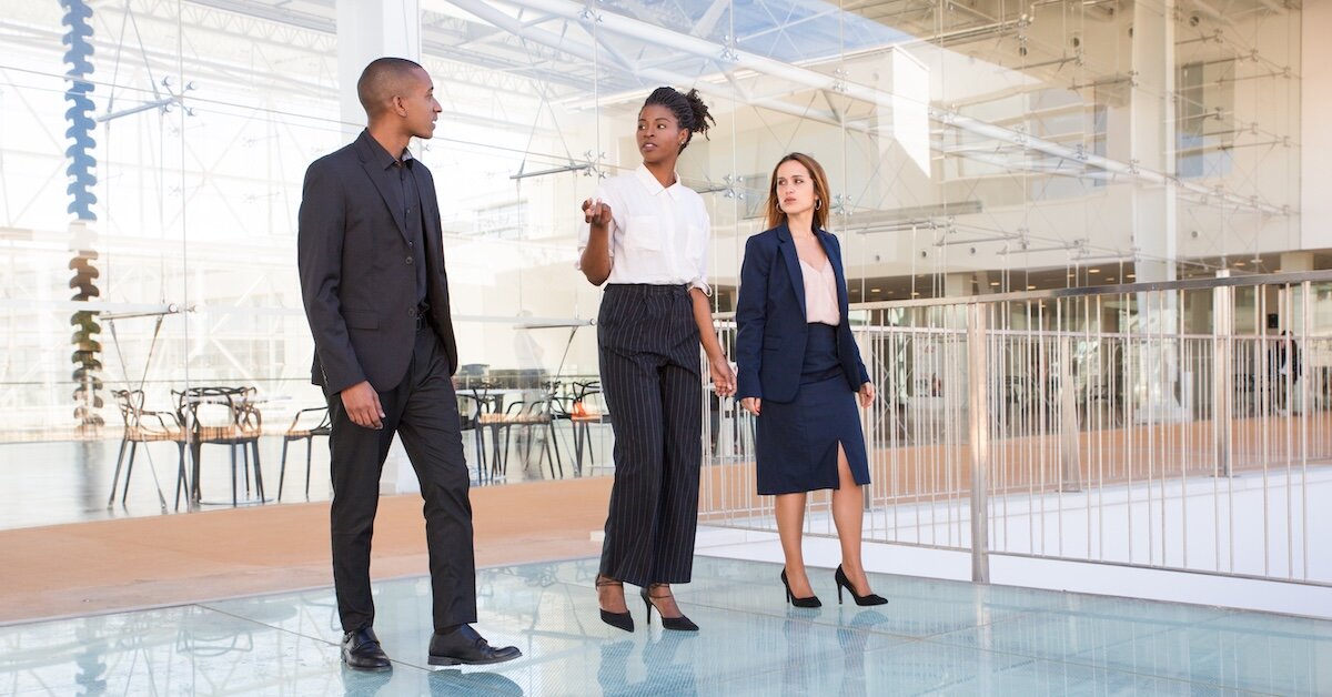 Three business professionals walk the foyer of a commercial building