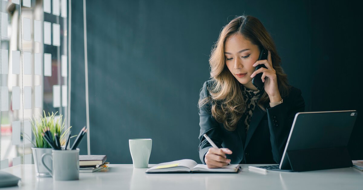 Woman taking notes while on a phone call