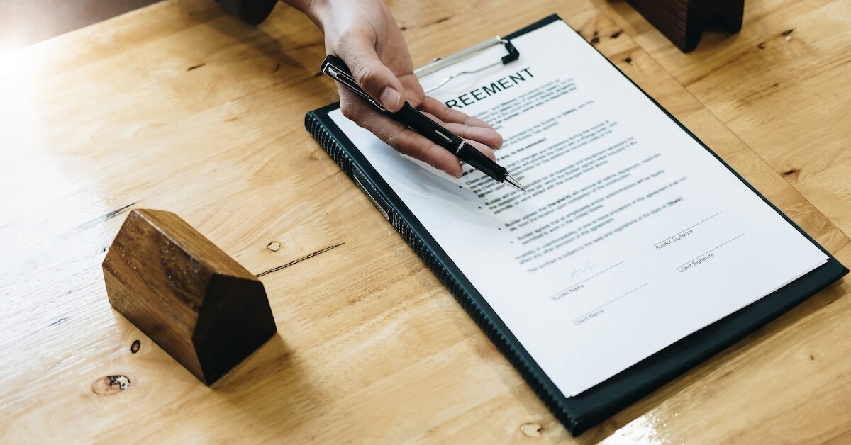 A rental agreement with a person holding a pen out to a signer