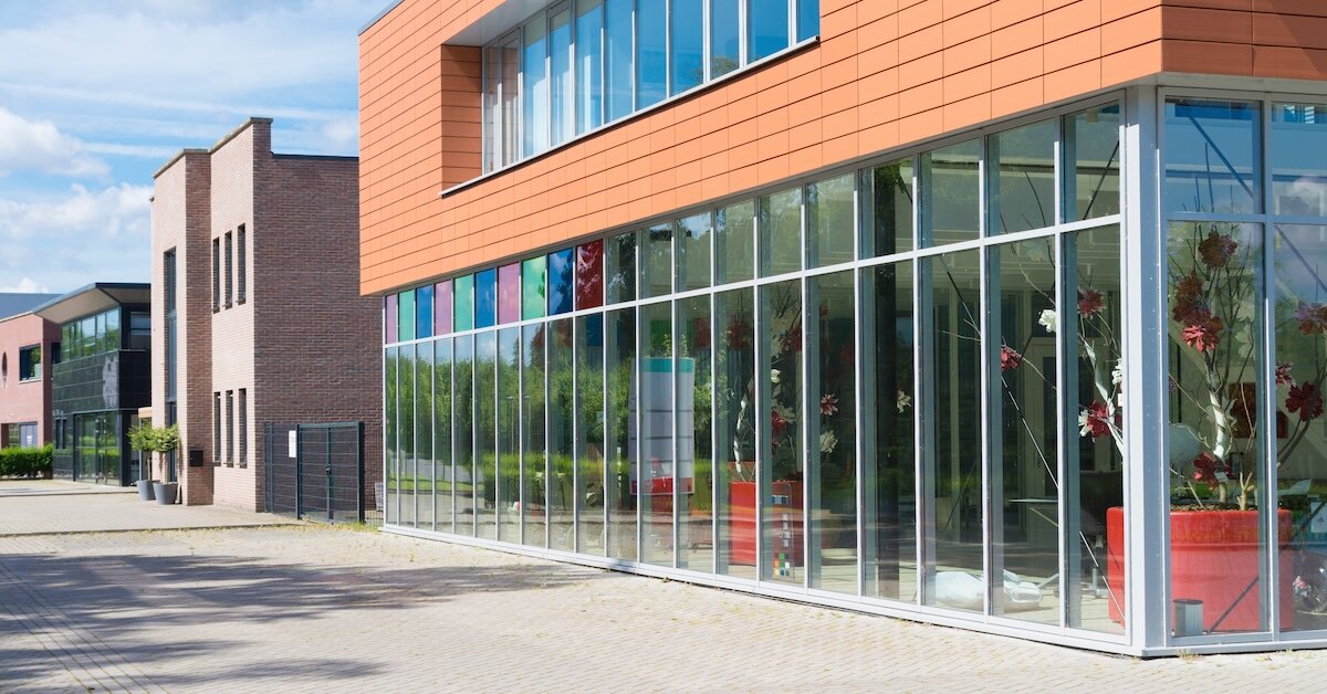 A commercial building with floor-to-ceiling windows shows different tenants on the inside