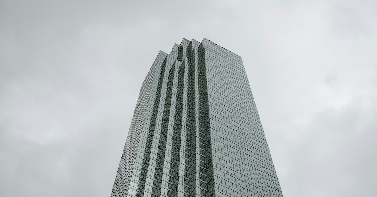 a tall skyscraper stands against a gray cloudy sky