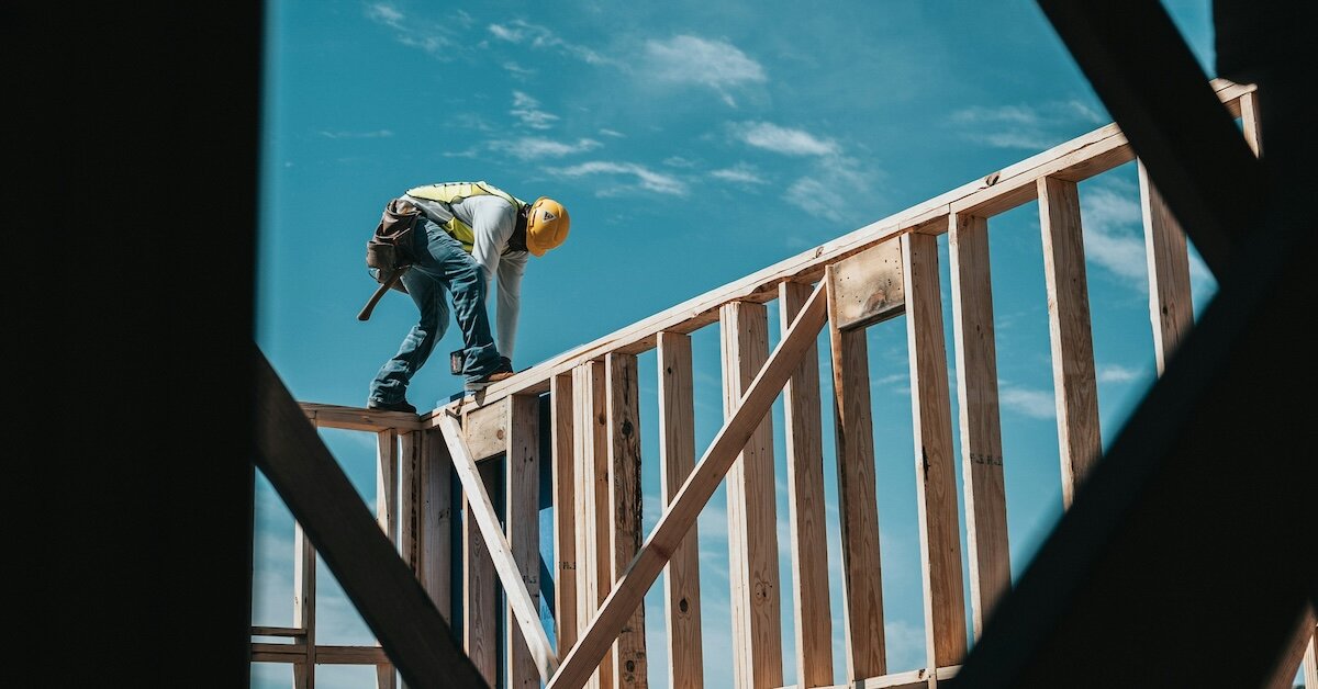 a construction worker bolts studs into the frame of a building