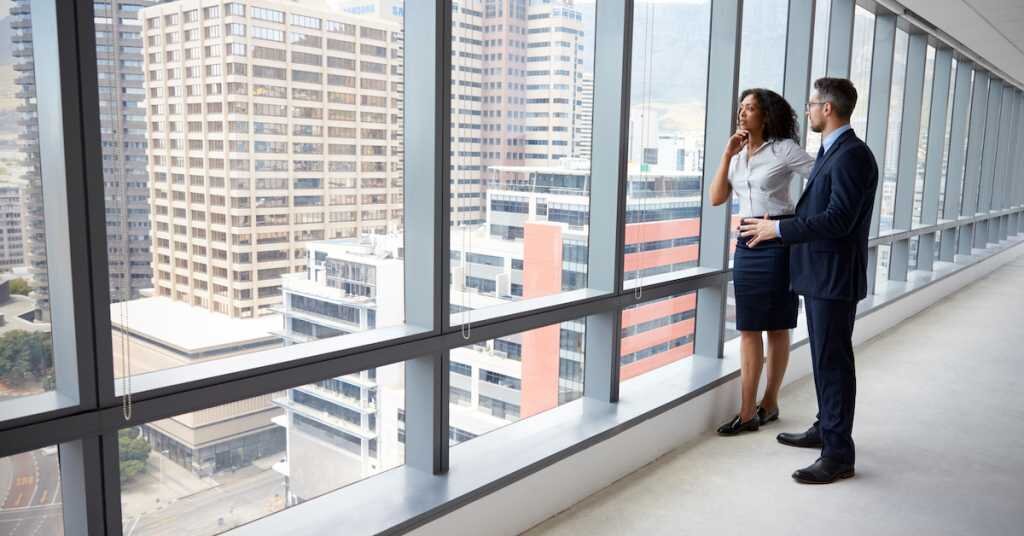 Portrait Of New Business Owners By Empty Office Window