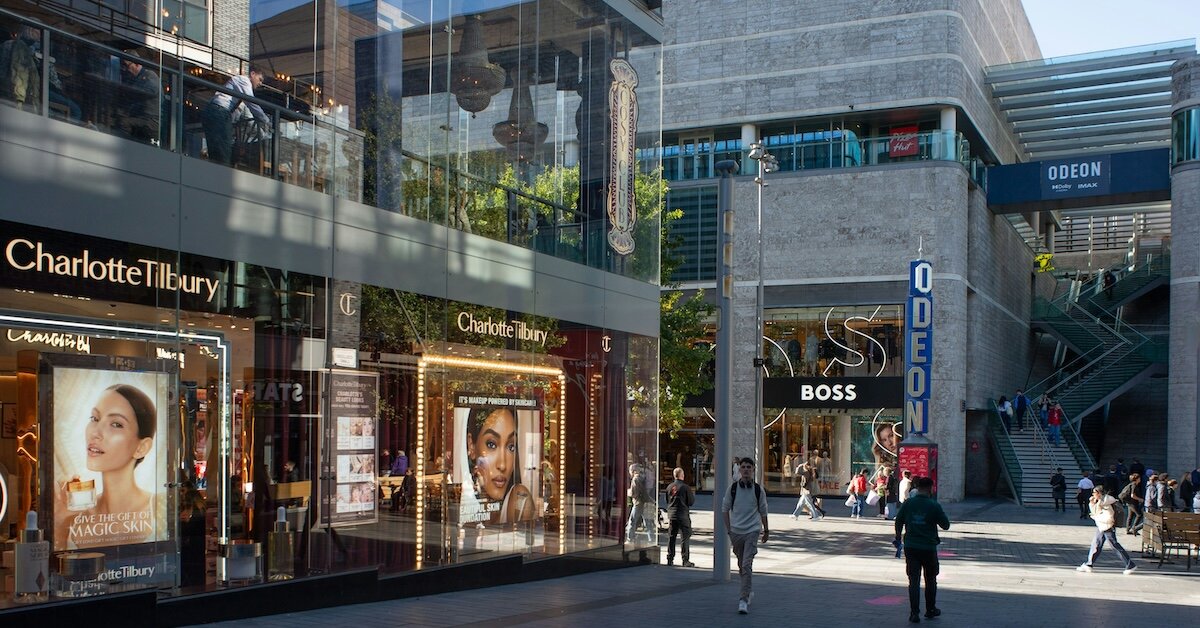 An outdoor mall with shoppers walking around in front of the retail stores