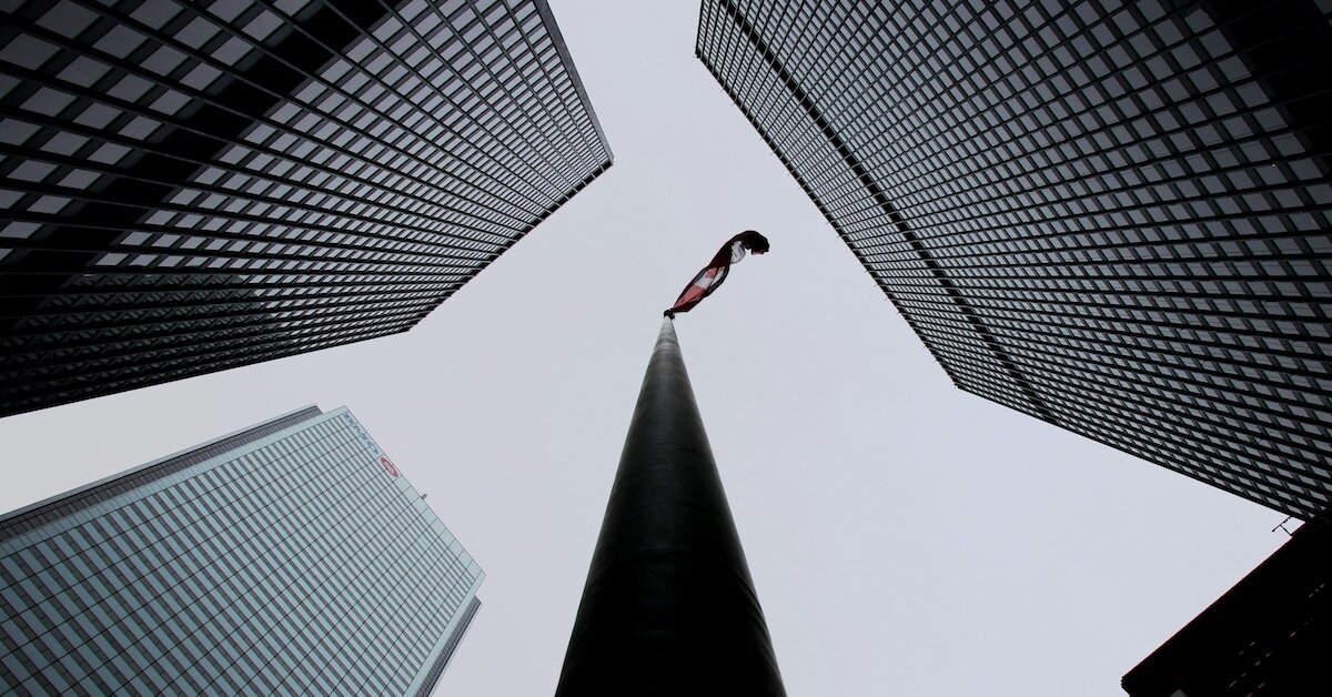 looking straight up at buildings, one with a flag waving