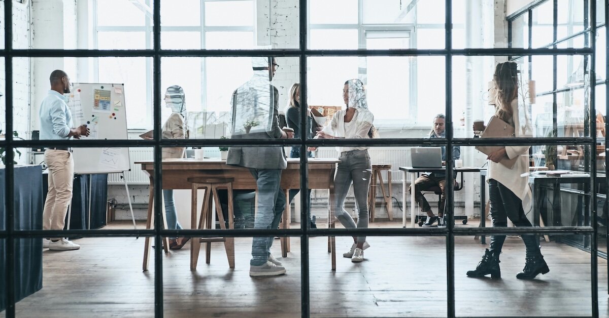 People walk around in a bustling office conference room