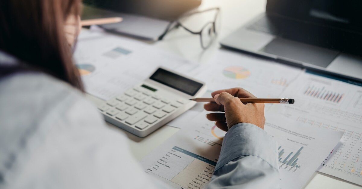 a woman tracking markets with paper and calculator