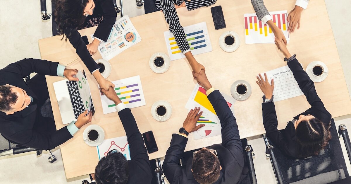 many business professionals shaking hands across a conference table