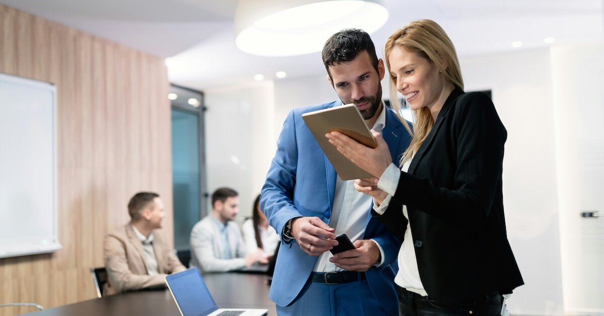 two brokers looking at a deal on an ipad
